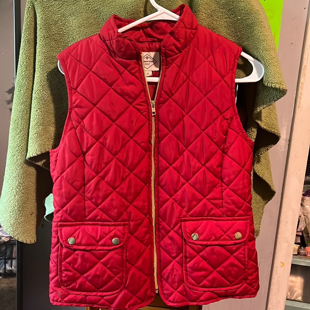 This is a St. John’s Bay Vest. It is a medium and is red with a golden zipper